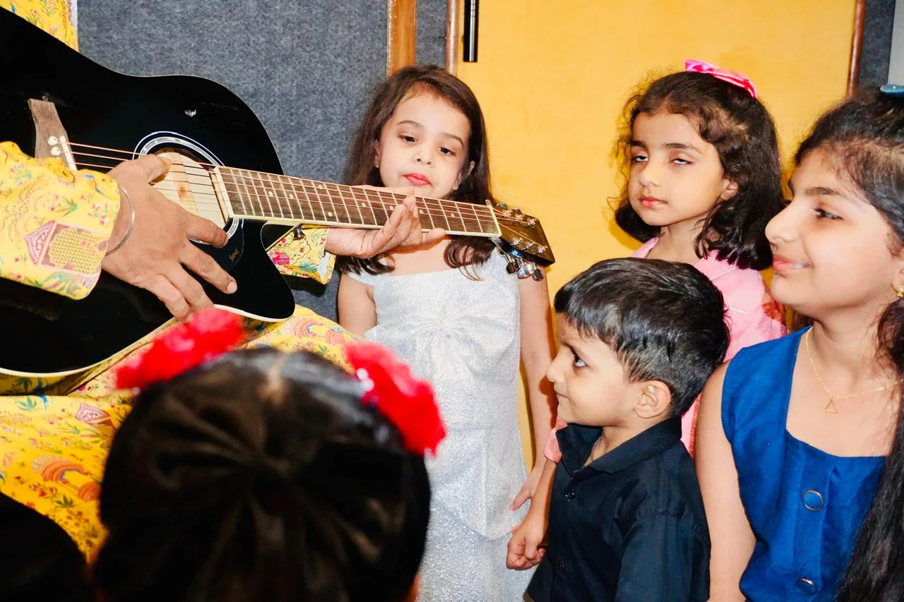 Young students learning around a guitar at CloudStudio108